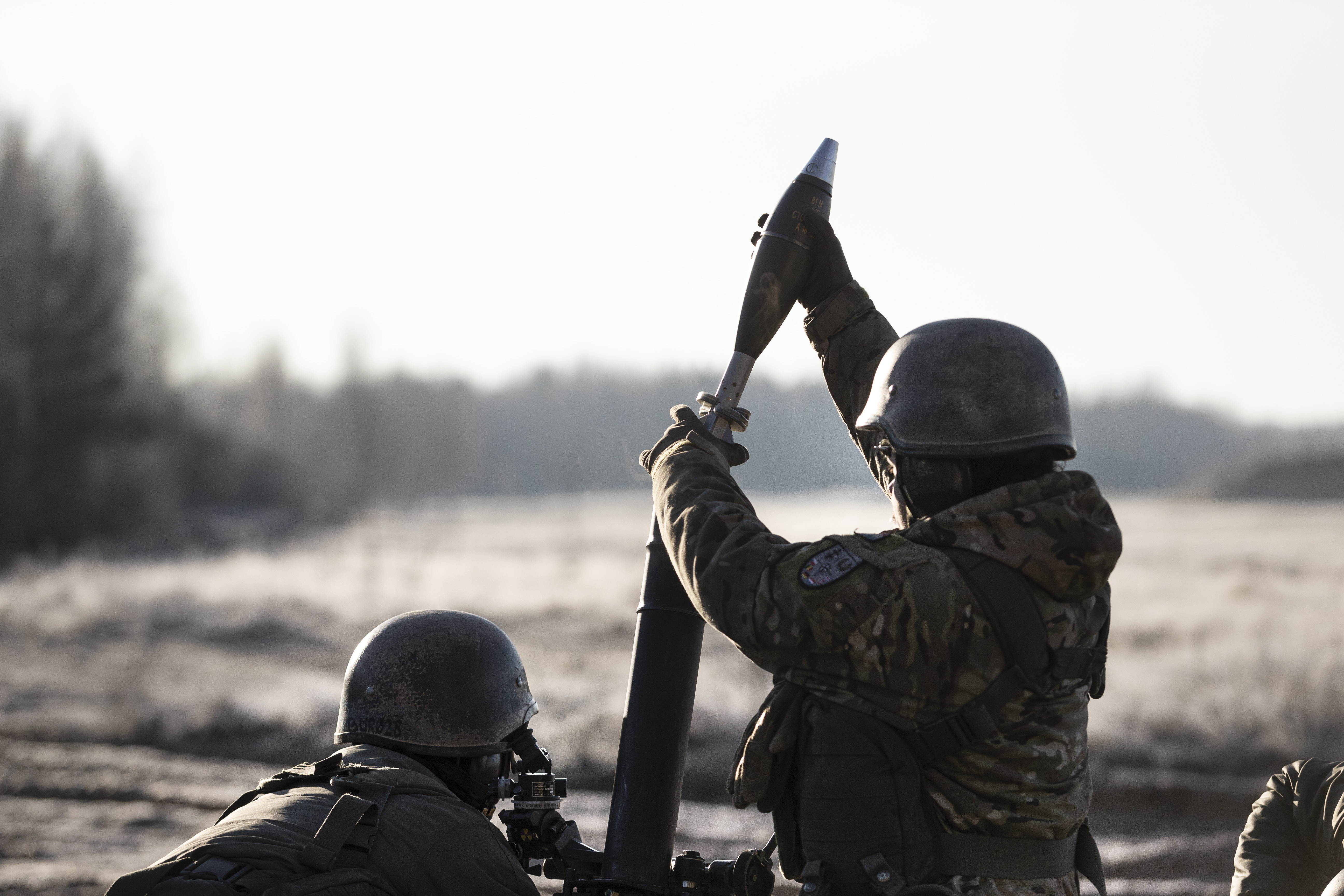 Archiefbeeld militairen die een 81mm mortiergranaat in een loop doen